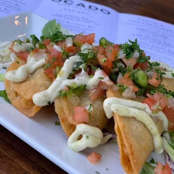 Ocado Restaurant's vegan tacos, topped with fresh salsa, cilantro, and a creamy white sauce.
